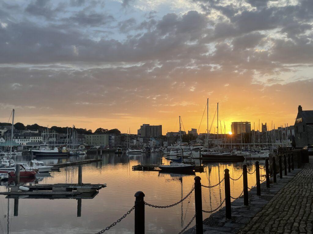 The sunset shines over Sutton Harbour, a popular spot for waterfront dining.