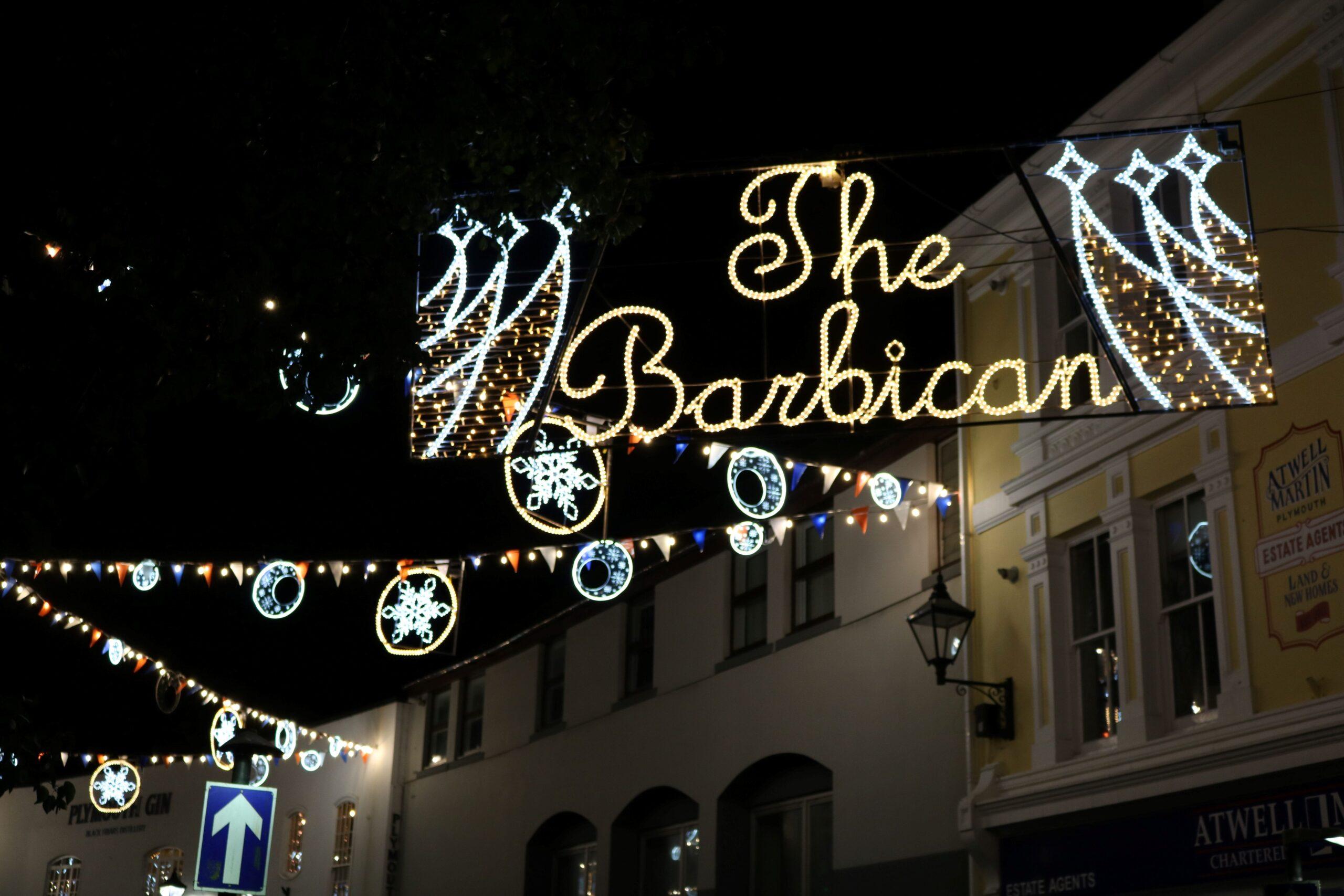 An image focusing in on a christmas light that reads 'the barbican' with twinkly star lights