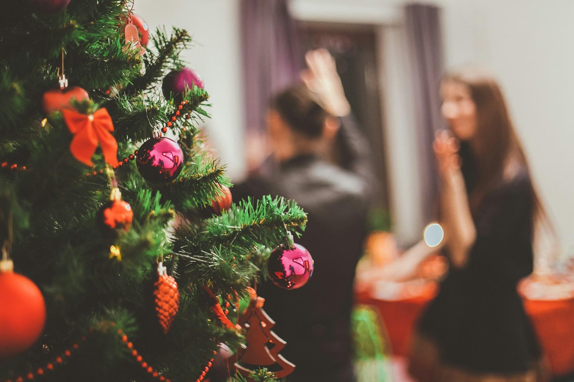 Close up of a christmas tree, blurry in the background we see two people dancing