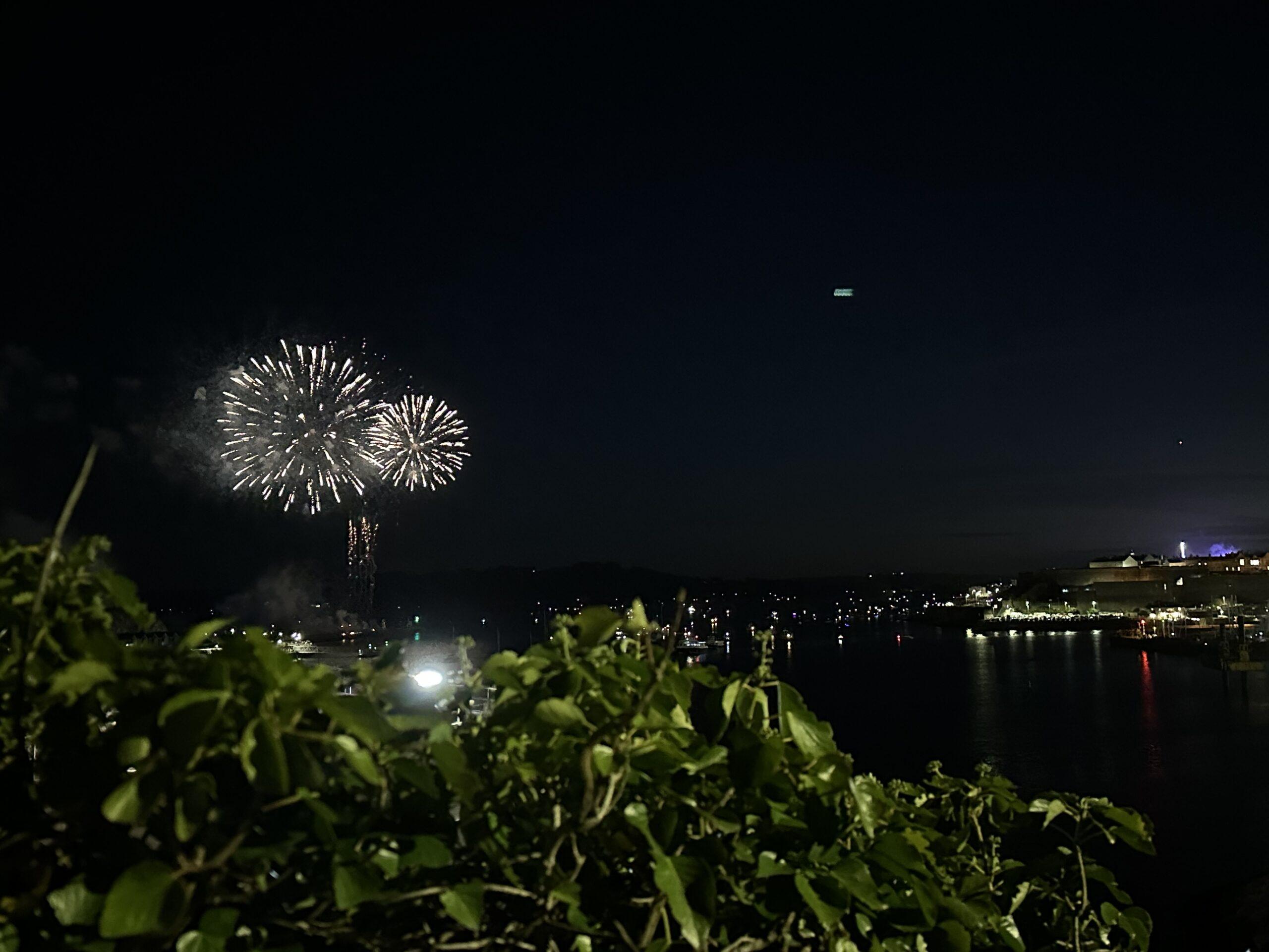 Golden fireworks sparkle above the Plymouth Sound and reflect on the water below