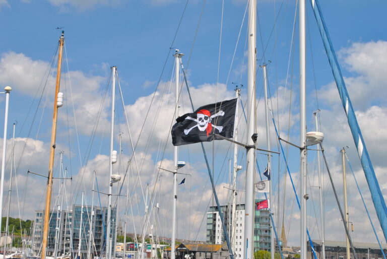 An image of a skull and crossbones flag flying on a boat mast in Sutton Harbour